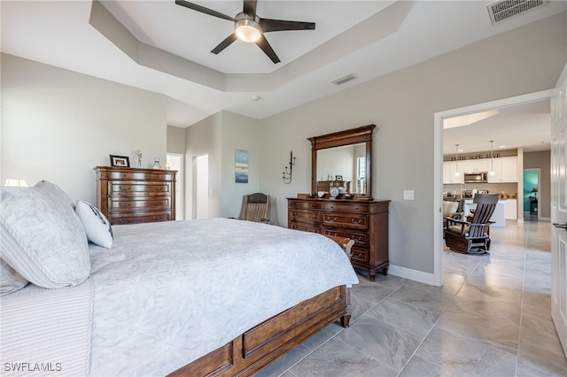 bedroom with visible vents, a ceiling fan, a raised ceiling, and baseboards