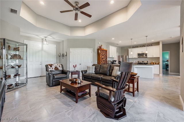 living area featuring visible vents, recessed lighting, a raised ceiling, and a ceiling fan