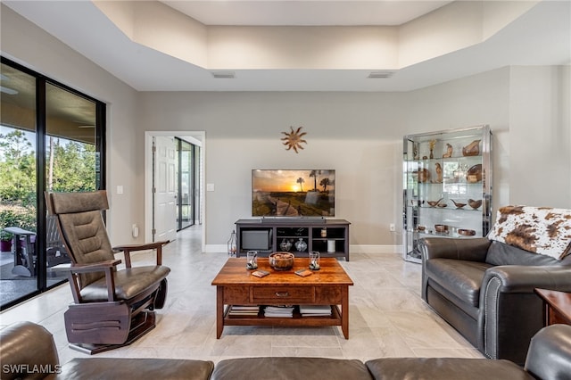 living room featuring visible vents, a raised ceiling, and baseboards