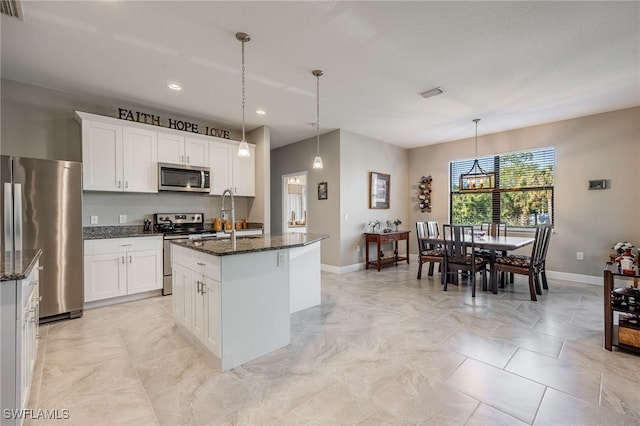 kitchen featuring white cabinetry, dark stone counters, a center island with sink, and appliances with stainless steel finishes