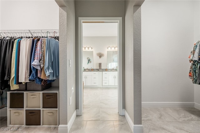 spacious closet featuring marble finish floor and a sink