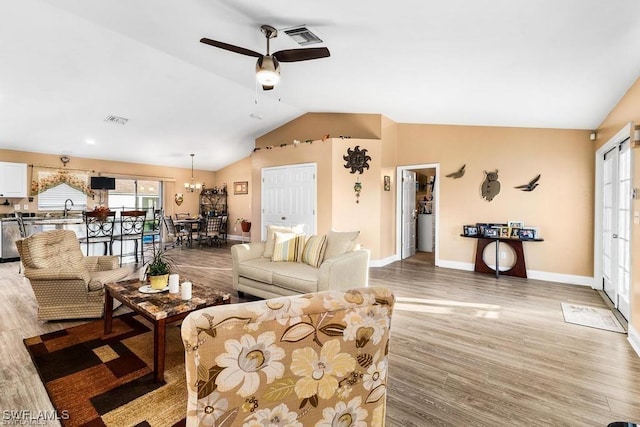 living room featuring visible vents, ceiling fan, baseboards, lofted ceiling, and wood finished floors