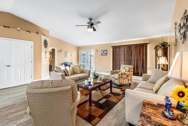 living area with baseboards, lofted ceiling, light wood-style floors, and ceiling fan