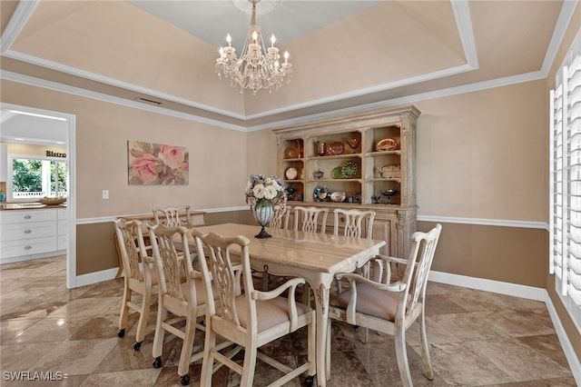 dining space with a tray ceiling, baseboards, a notable chandelier, and ornamental molding