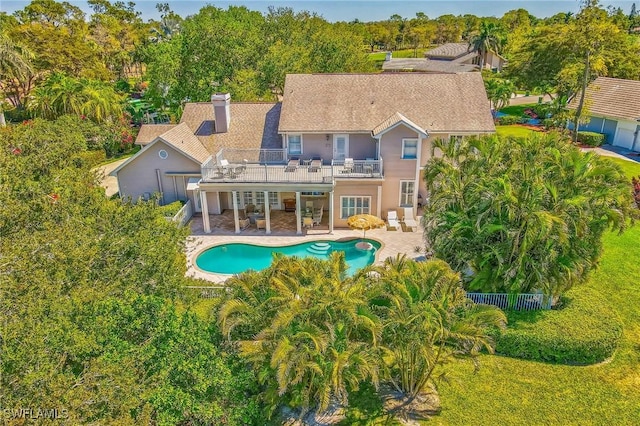 back of house with a balcony, a patio area, an outdoor pool, and a chimney