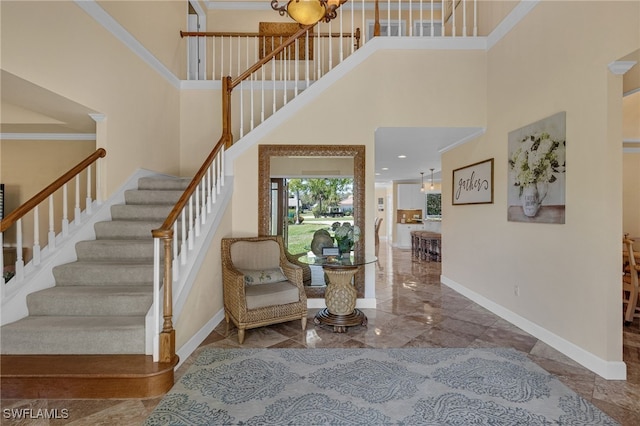 entrance foyer featuring crown molding, baseboards, stairs, a towering ceiling, and marble finish floor