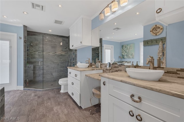 bathroom featuring crown molding, toilet, visible vents, and a stall shower