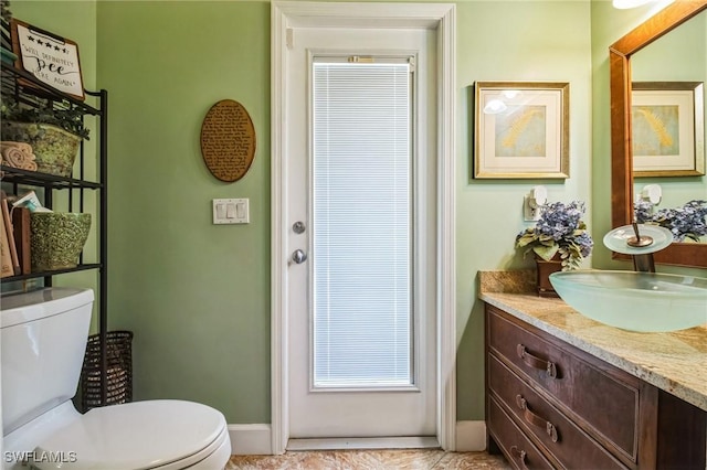 bathroom featuring toilet, vanity, and baseboards