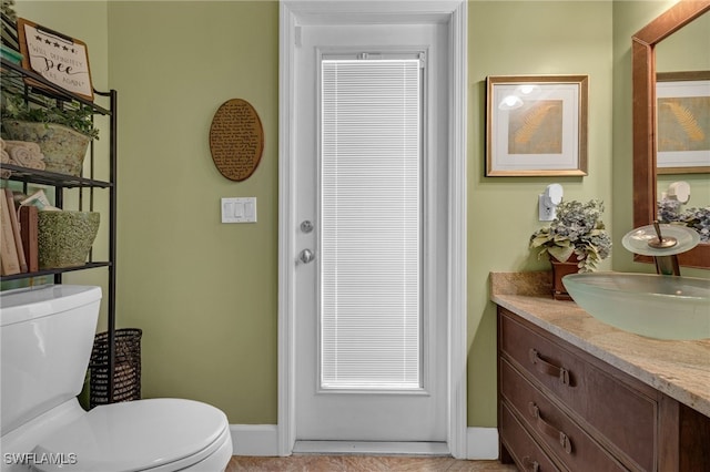 bathroom featuring vanity, toilet, and baseboards