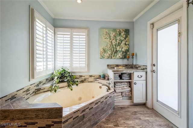 full bath featuring wood finished floors, a jetted tub, ornamental molding, and vanity