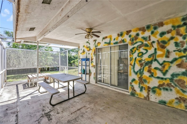 view of patio featuring glass enclosure, outdoor dining space, and a ceiling fan