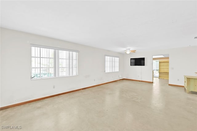 unfurnished living room with a ceiling fan, finished concrete flooring, and baseboards