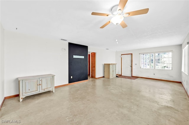 unfurnished living room with ceiling fan, concrete floors, and baseboards