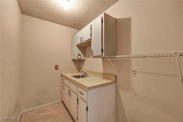 clothes washing area featuring baseboards and a sink