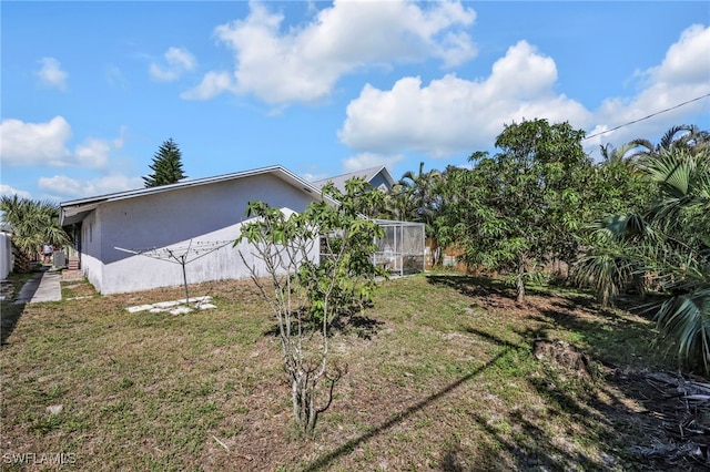 view of side of property featuring stucco siding and a yard