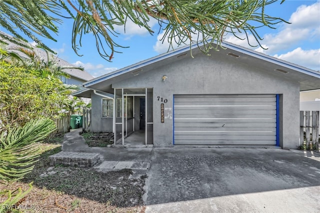 view of front of home with stucco siding, a garage, concrete driveway, and fence