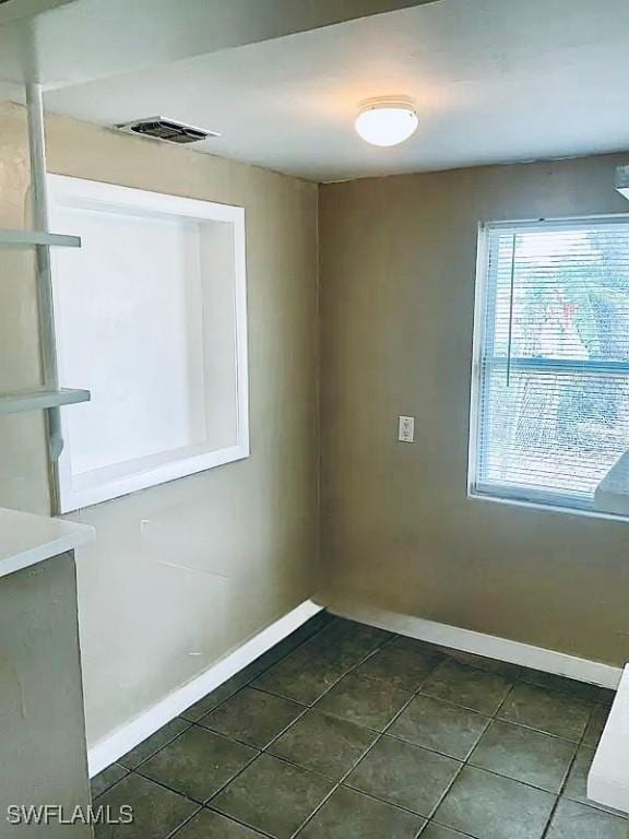 empty room with visible vents, baseboards, and dark tile patterned flooring