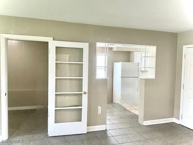 interior space with tile patterned floors, built in shelves, and baseboards