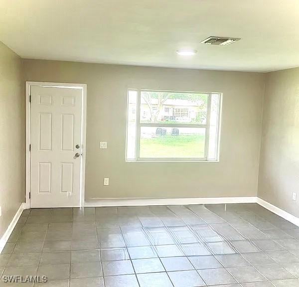 tiled empty room with visible vents and baseboards