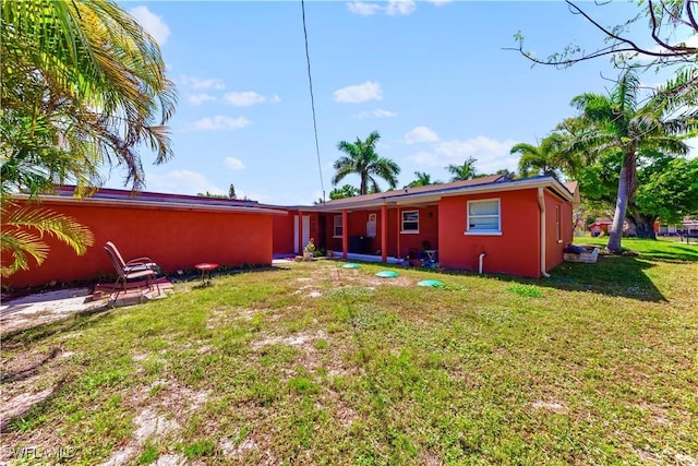 rear view of property with stucco siding and a lawn