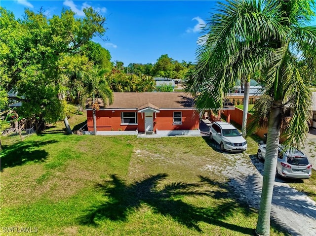 rear view of property featuring a lawn and dirt driveway