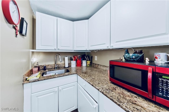 kitchen featuring white cabinets, light stone countertops, and a sink