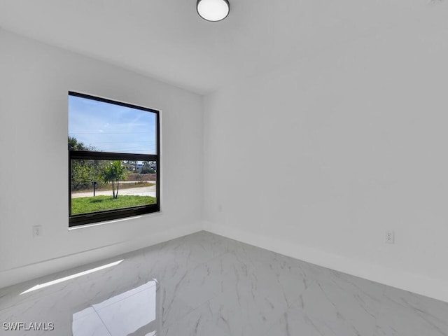 spare room featuring baseboards and marble finish floor