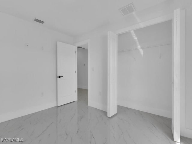 unfurnished bedroom featuring visible vents, baseboards, marble finish floor, and a closet