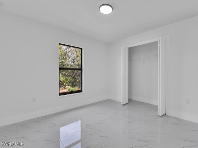 unfurnished bedroom featuring a closet, baseboards, and marble finish floor