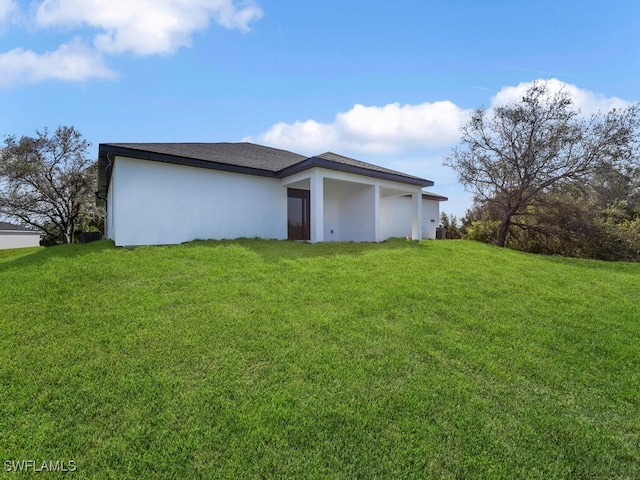 back of property with stucco siding and a lawn