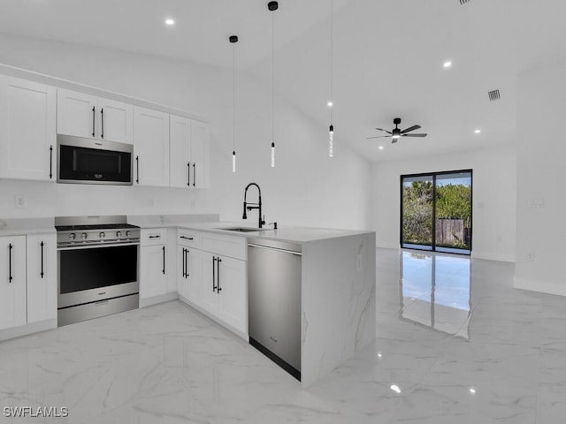 kitchen featuring a peninsula, a sink, marble finish floor, appliances with stainless steel finishes, and open floor plan