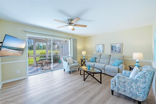 living area featuring baseboards, a ceiling fan, and wood finished floors