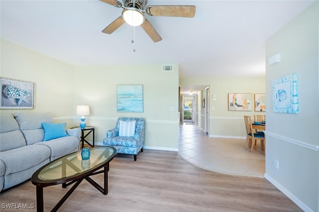 living area with light wood-style flooring, baseboards, visible vents, and ceiling fan