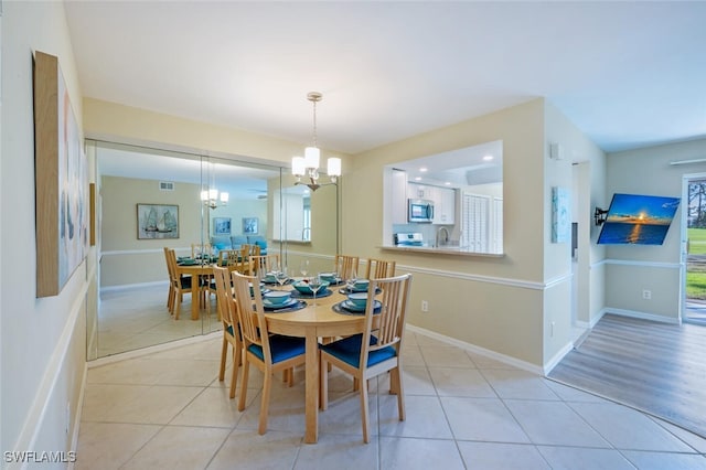 dining room with light tile patterned floors, baseboards, and a notable chandelier