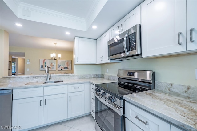 kitchen featuring ornamental molding, white cabinetry, appliances with stainless steel finishes, a raised ceiling, and a chandelier