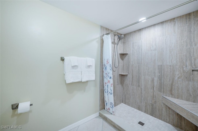 full bathroom featuring baseboards and a tile shower