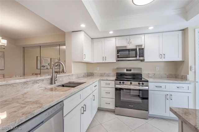 kitchen with a sink, white cabinetry, appliances with stainless steel finishes, crown molding, and light stone countertops