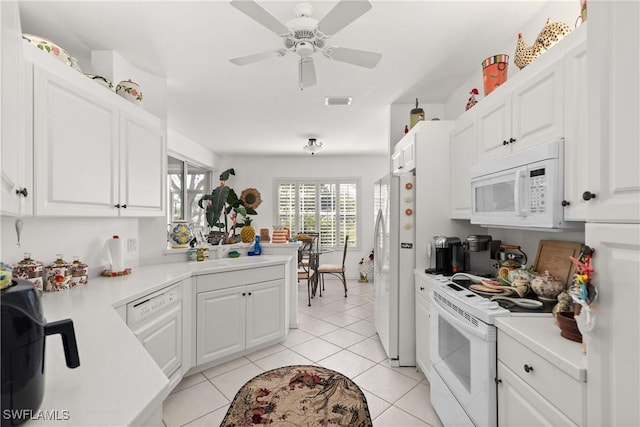 kitchen with light tile patterned floors, white appliances, white cabinets, and light countertops