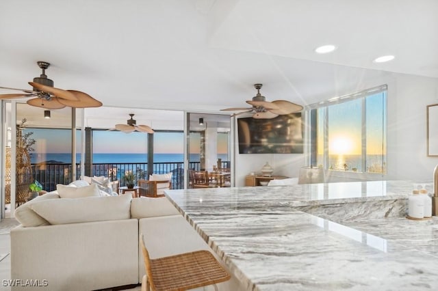 living area featuring recessed lighting, a ceiling fan, a water view, and expansive windows