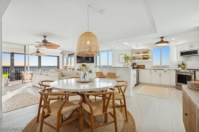 dining space featuring a ceiling fan and a tray ceiling