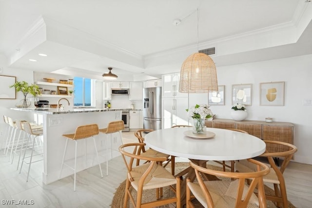 dining space with a raised ceiling, visible vents, and ornamental molding