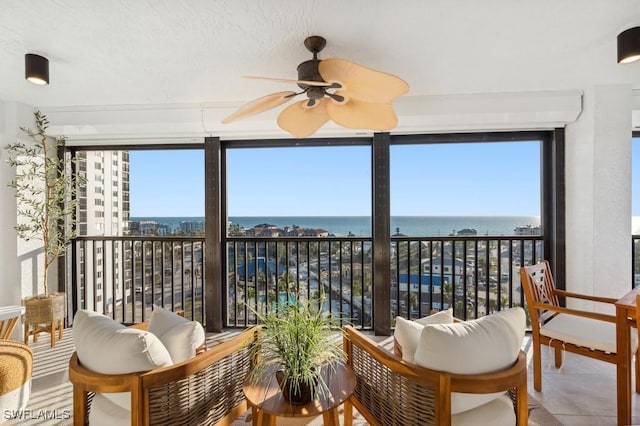 sunroom featuring a water view and ceiling fan