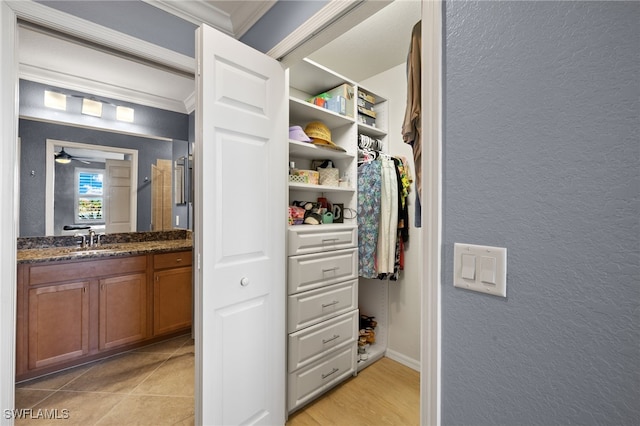 spacious closet featuring light tile patterned floors, a ceiling fan, and a sink