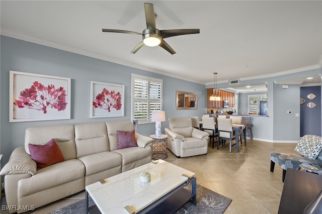 living room featuring light tile patterned floors, a ceiling fan, baseboards, visible vents, and ornamental molding