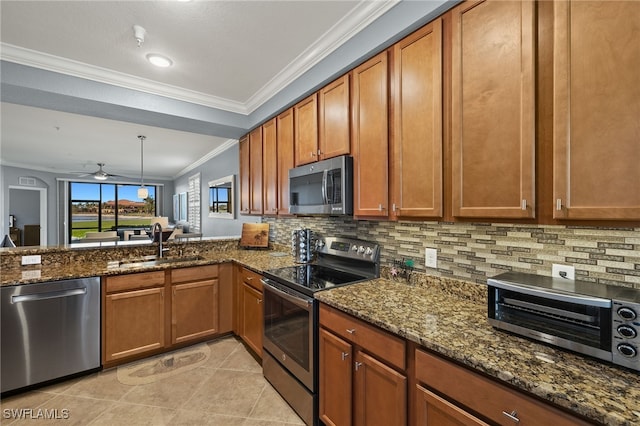 kitchen with a sink, stainless steel appliances, a ceiling fan, and dark stone counters