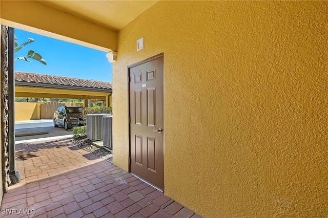 property entrance with stucco siding and central AC