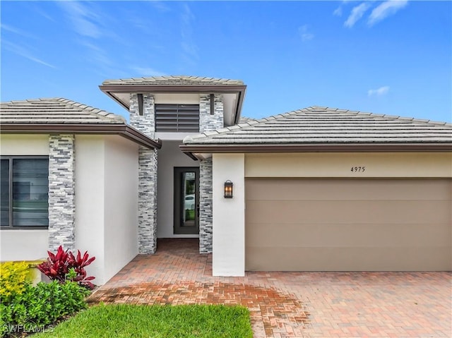 exterior space with stucco siding, a tile roof, decorative driveway, and a garage