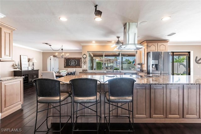 kitchen featuring dark wood-type flooring, crown molding, island exhaust hood, and stainless steel fridge