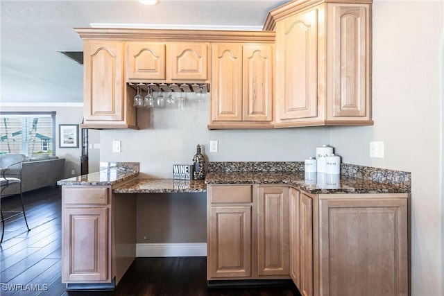 kitchen featuring light brown cabinetry, dark stone counters, and dark wood-style flooring