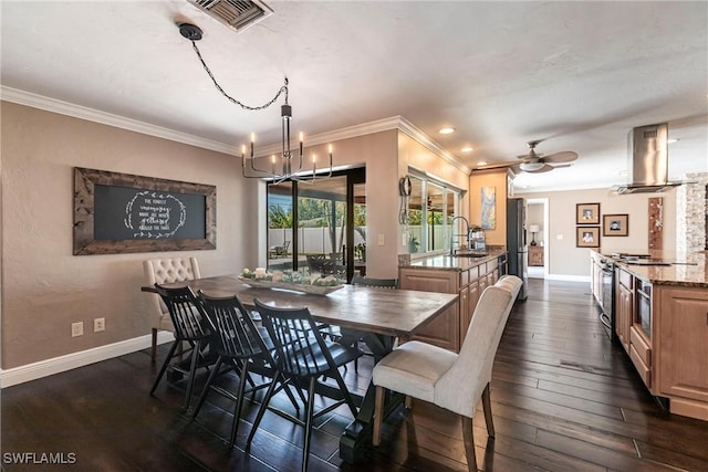 dining room featuring visible vents, dark wood-type flooring, ceiling fan with notable chandelier, crown molding, and baseboards